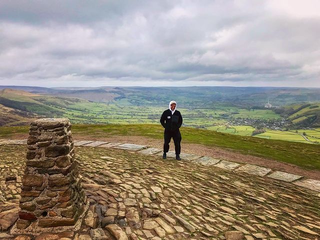 A photo of me on top of Mam Tor in the Peak District on a windy day