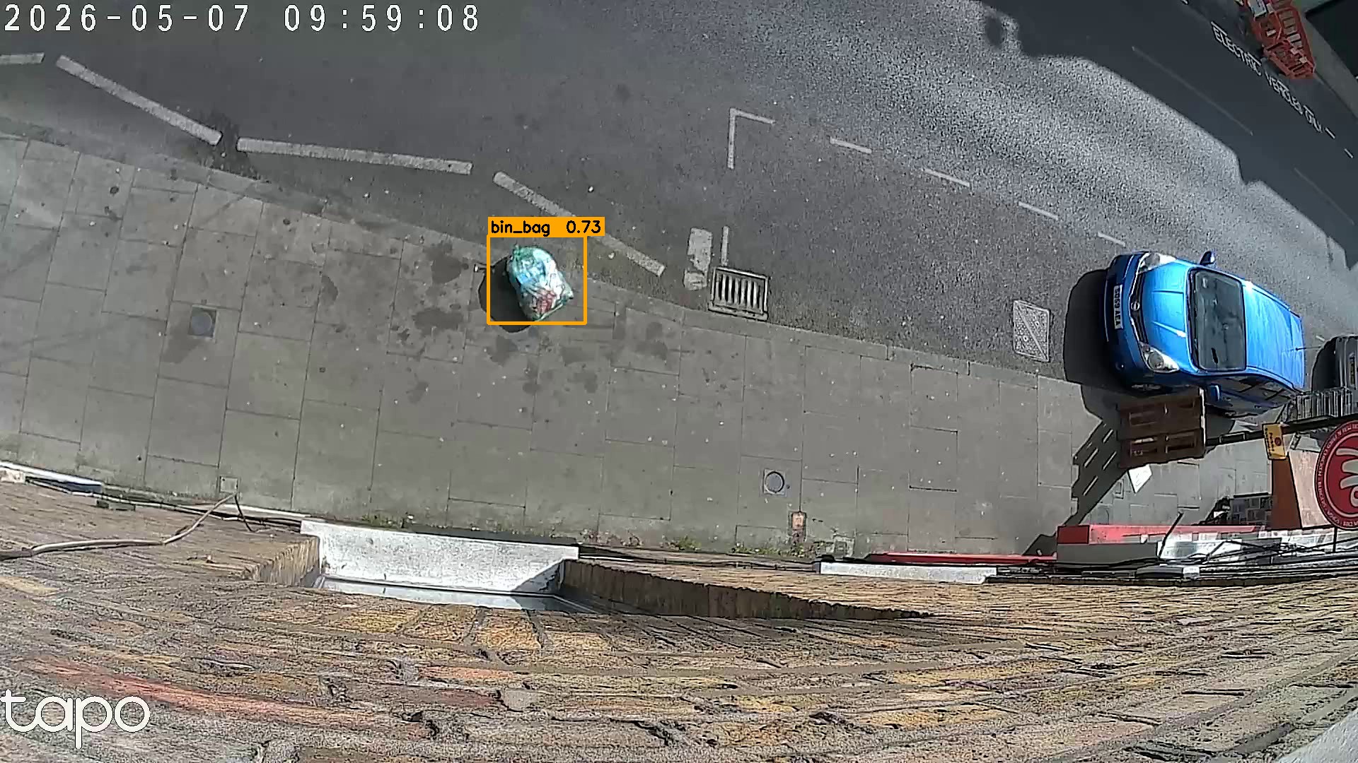 Annotated camera frame showing a bin bag detected on a pavement